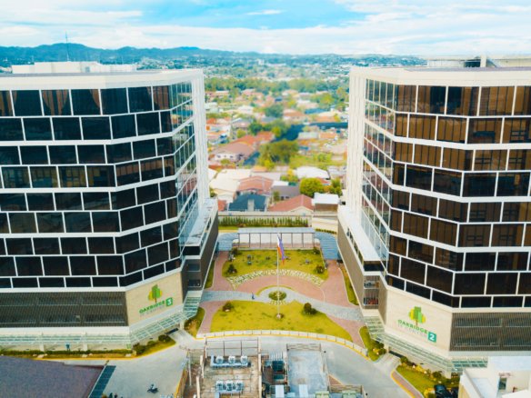 Aerial view of two curved glass office towers facing each other with a landscaped central courtyard at Oakridge Centre