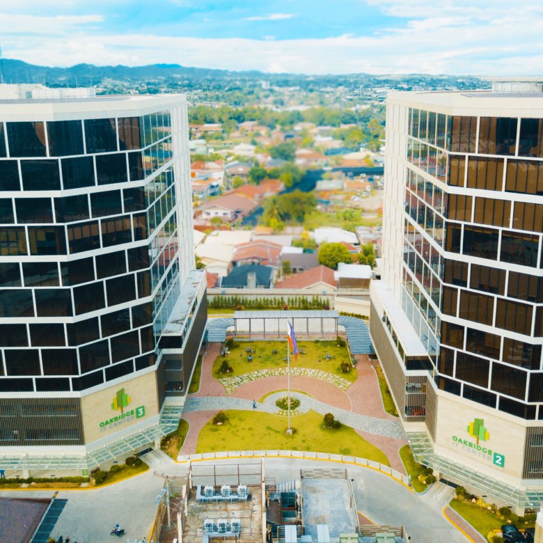 Aerial view of two curved glass office towers facing each other with a landscaped central courtyard at Oakridge Centre