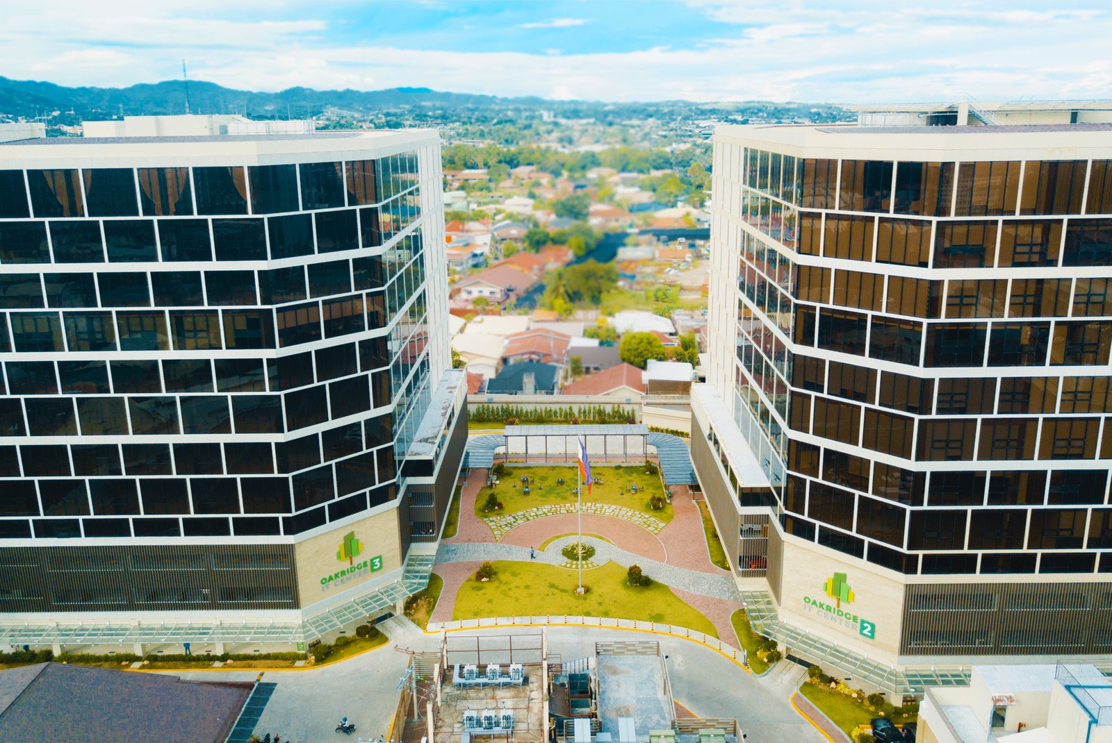 Drone Aerial view of two curved glass office towers facing each other with a landscaped central courtyard at Oakridge Centre