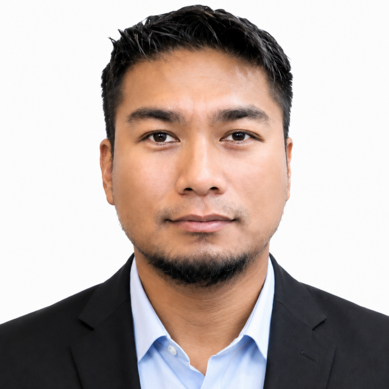 Professional headshot of a man in a black suit and light blue shirt, facing the camera against a white background.