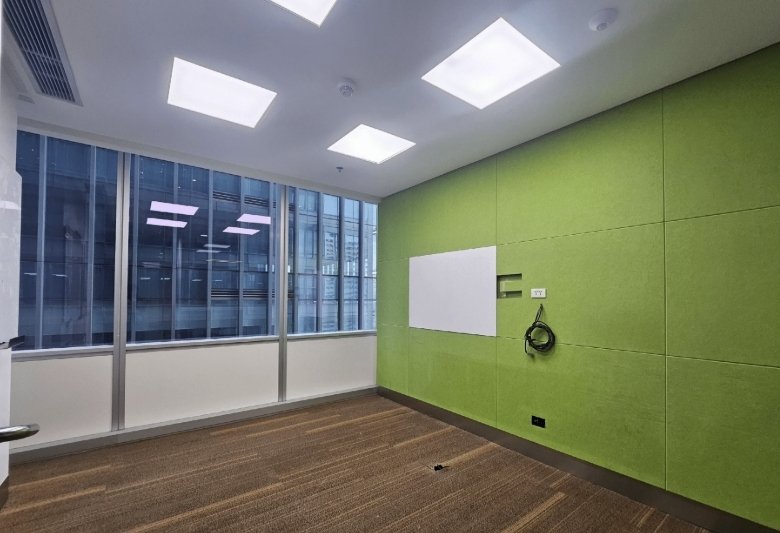 Empty modern office with lime-green wall, whiteboard, and large windows overlooking the city; bright square ceiling lights.