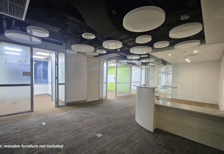 Open office lobby with glass partitions, a white curved reception desk, and round white ceiling panels.