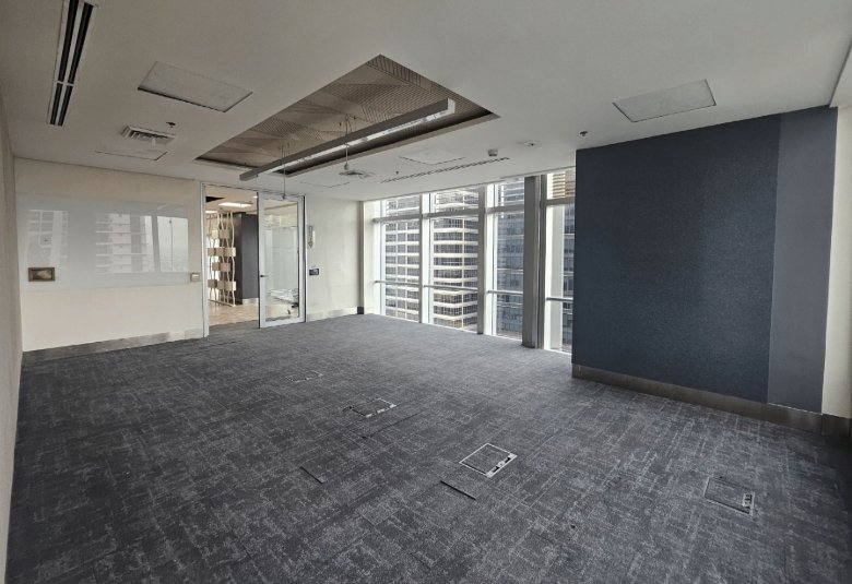 Empty high-rise office space with floor-to-ceiling windows and a blue accent wall on the right.