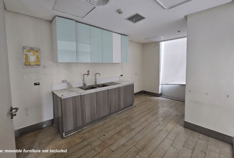 Empty kitchenette with a double sink, grey wood base cabinets, pale blue wall cabinets, and a large window with blinds.