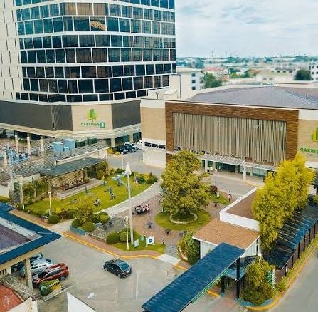 A modern medical campus with a tall glass building, low-rise connected pavilions, and a central courtyard with trees and walkways.