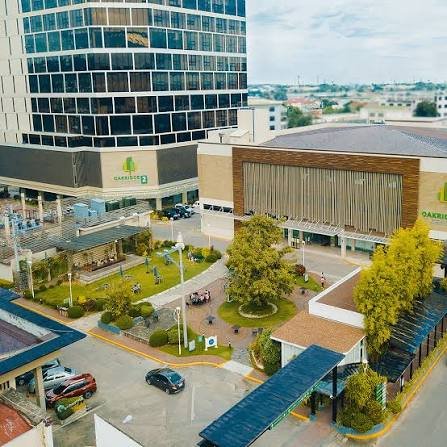 A modern medical campus with a tall glass building, low-rise connected pavilions, and a central courtyard with trees and walkways.