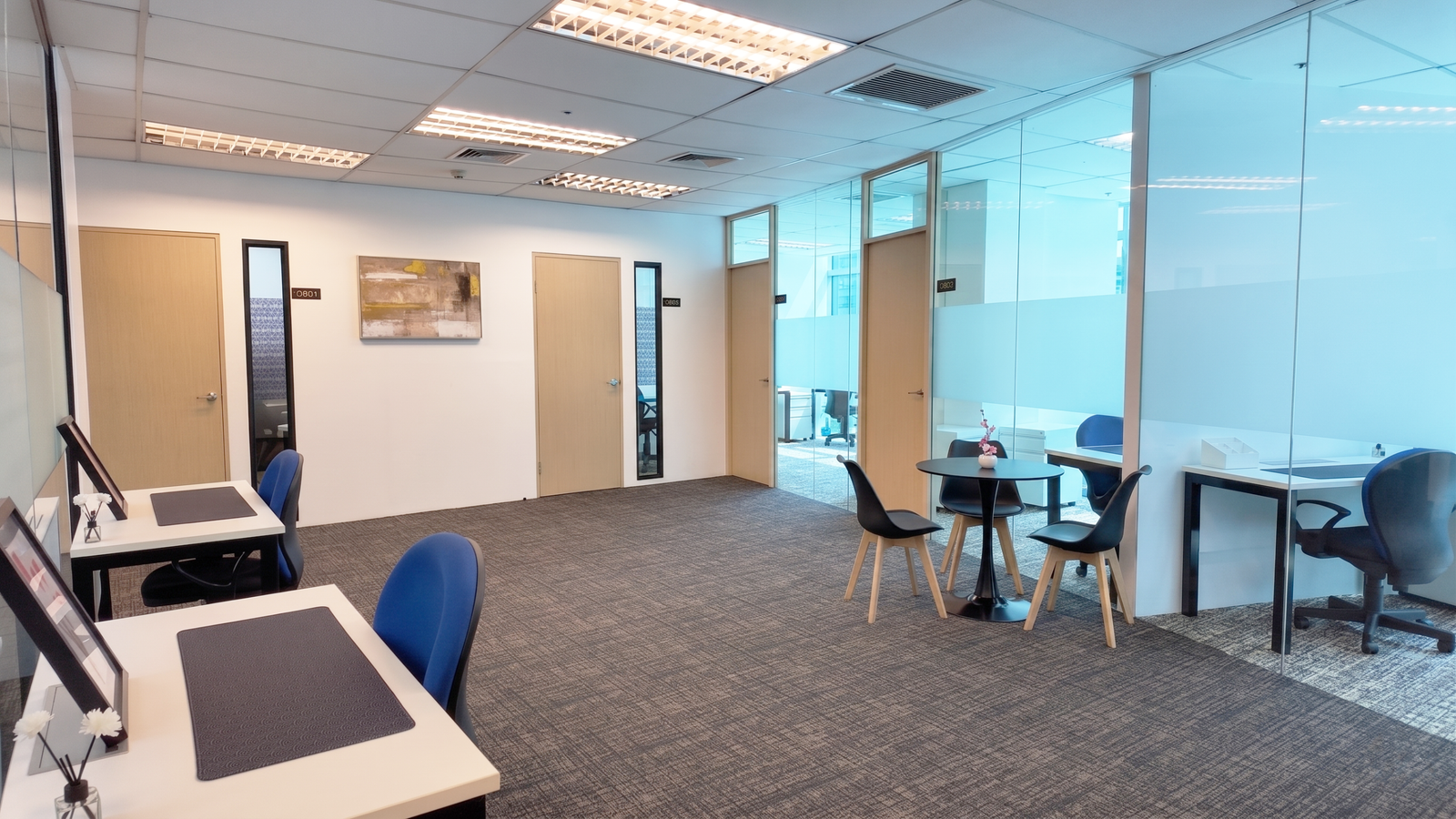 Work Space, Ortigas Modern open-plan office with glass-walled meeting rooms, light wood doors, and a seating area with blue chairs and tables.